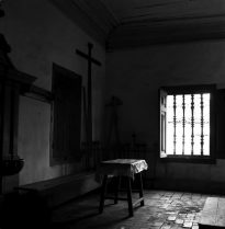 Foto preto e branca da sacristia de uma Igreja Matriz, com mesa, bancos e janela