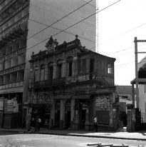 Imagem da Rua da Bahia em primeiro plano, contendo a fachada de dois prédios e pessoas caminhando na calçada.